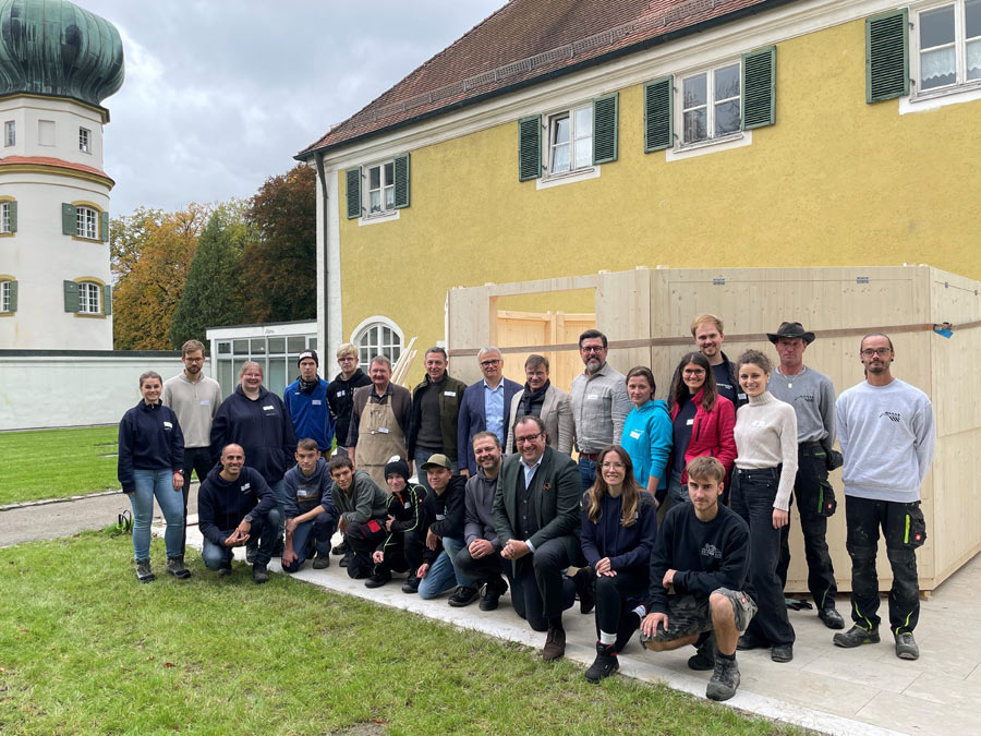 Gruppenbild mit allen Helfern und Verantwortlichen vor dem Verkaufspavillon aus Holz