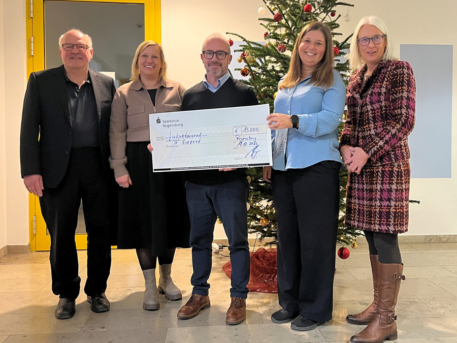 Bei der Spendenübergabe vor einem Weihnachtsbaum Peronen mit dem Spendenscheck