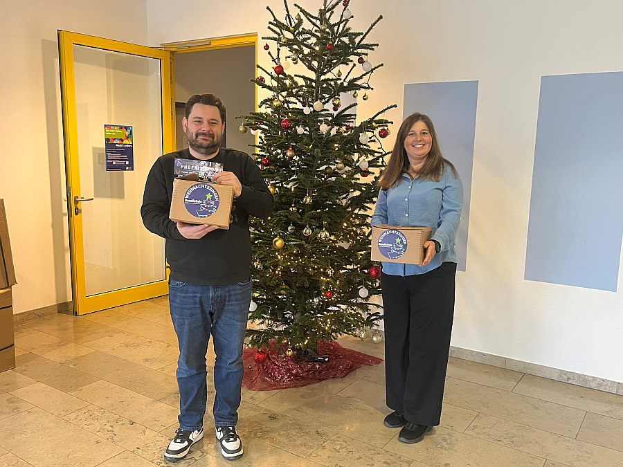 Markus Guggenberger und Daniela Wanderer mit Geschenkpäckchen beim Christbaum stehend