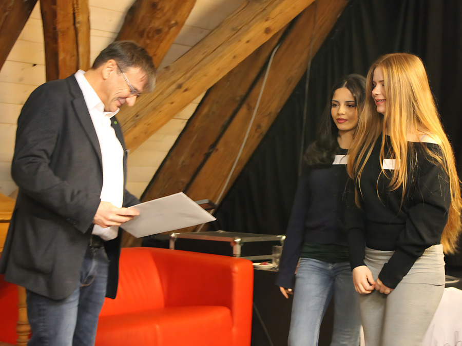 zwei junge Frauen überreichen Michael Eibl die Ehrenurkunde