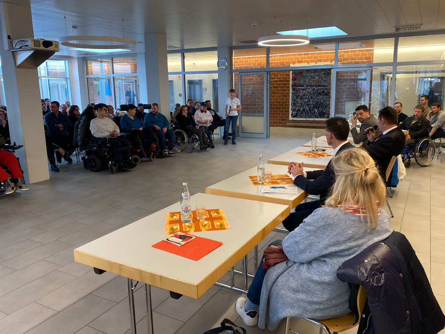 Werkstatträtin Erika Stelzl moderierte die Podiumsdiskussion. Sie steht vor dem Publikum mit einem Mikrofon.