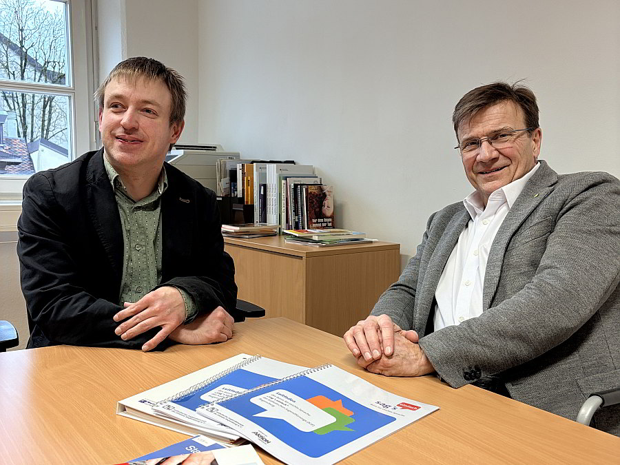 Sebastian Müller und KJF-Direktor Michael Eibl sitzen zusammen und unterhalten sich.