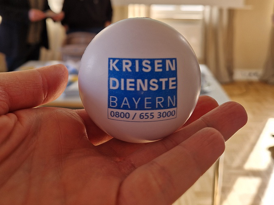 Hand hält Ball mit Aufschrift: Krisendienste Bayern