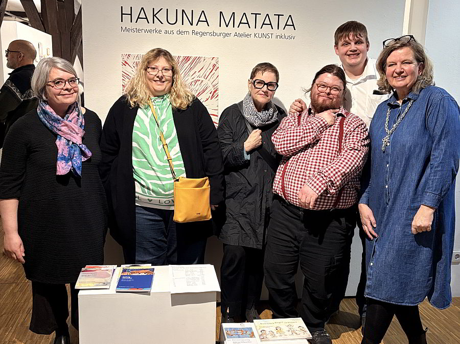 Gruppenbild im Kornhaus vor Ausstellungsplakat mit der Leiterin des Ateliers Kunst inklusiv, den Künstlern und der Vorsitzenden des Gmünder Kunstvereins