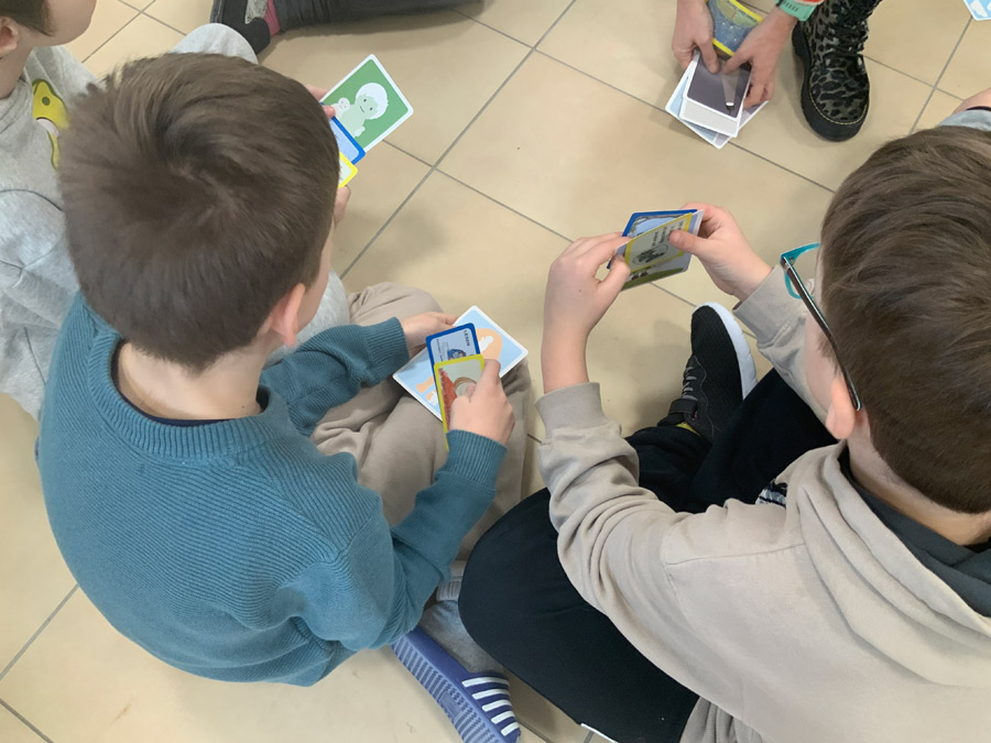 Kinder spielen Karten als Teil eines Projekts über Fairness und Teamgeist.