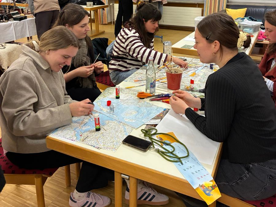 Junge Menschen sitzen gemeinsam am Tisch und basteln Perlen.
