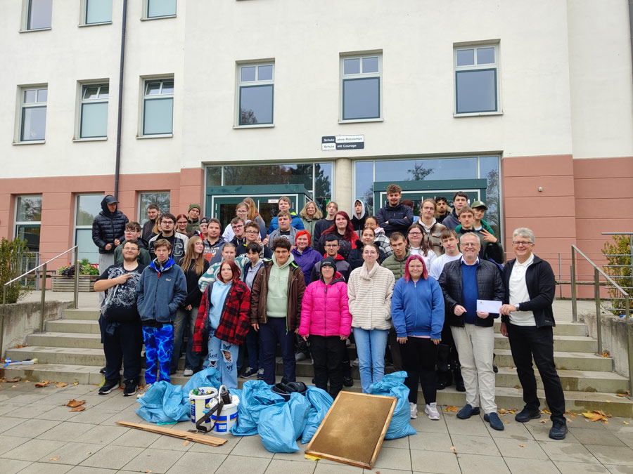 Schülerinnen und Schüler mit gesammeltem Müll in Säcken vor der Schule